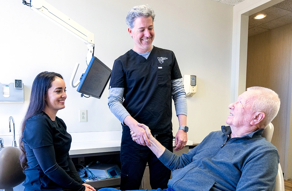 Dr. Andrew Jackson DDS greeting an older male patient with a handshake in the Nashville dental office